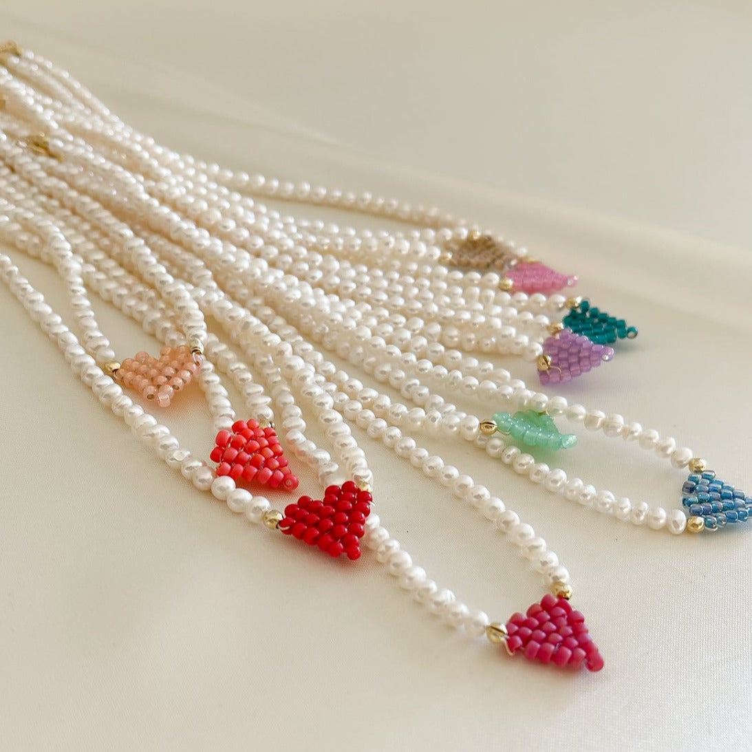 Collana di perle di fiume modello girocollo-coker  con in centro cuore in perline toho di colori diversi.  La collana CUORE nasce con lo scopo di celebrare l'amore.  MATERIALE: perle di fiume, perline toho, componenti e moschettone in argento 925 con galvanica color oro. DIMENSIONI: lunghezza collana: circa 39 cm + 4 cm catenella CUORE in perline di diversi colori a scelta: smeraldo-verde acqua-blu-vioa-pink- rosso scuro mat- rrosso-arancione mat-rosa baby-oro opaco mat