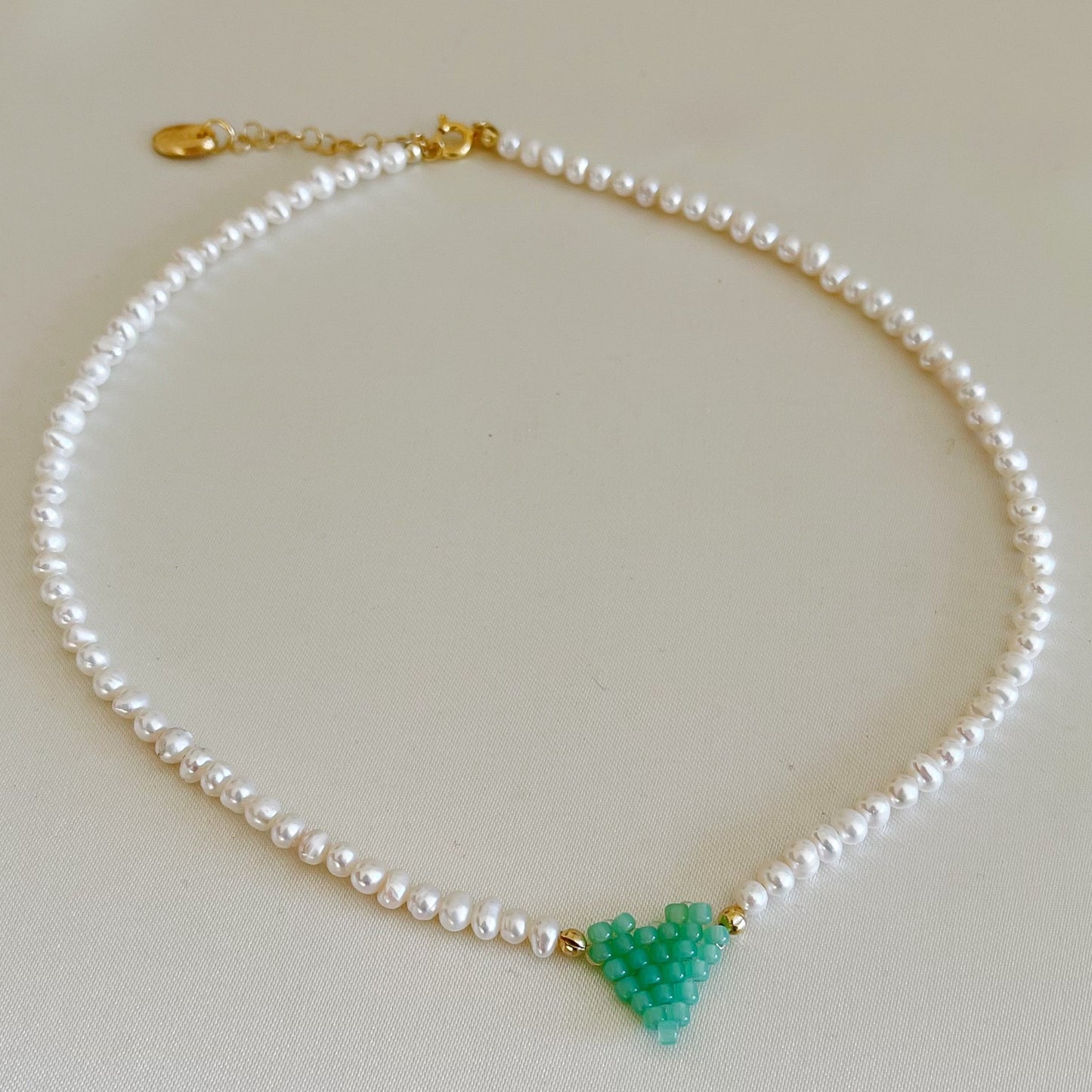 Collana di perle di fiume modello girocollo-coker  con in centro cuore in perline toho di colori diversi.  La collana CUORE nasce con lo scopo di celebrare l'amore.  MATERIALE: perle di fiume, perline toho, componenti e moschettone in argento 925 con galvanica color oro. DIMENSIONI: lunghezza collana: circa 39 cm + 4 cm catenella CUORE in perline di diversi colori a scelta: smeraldo-verde acqua-blu-vioa-pink- rosso scuro mat- rrosso-arancione mat-rosa baby-oro opaco mat