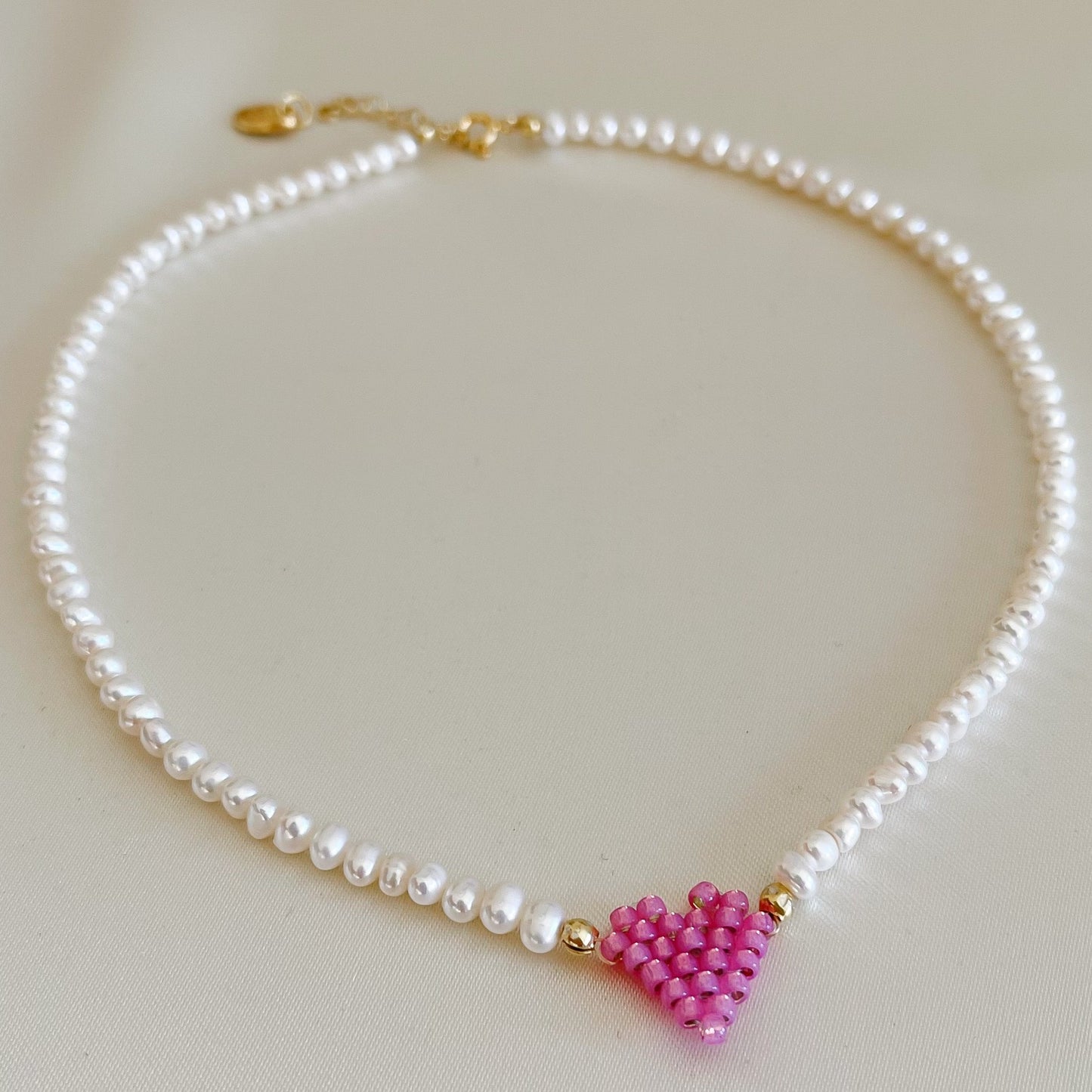 Collana di perle di fiume modello girocollo-coker  con in centro cuore in perline toho di colori diversi.  La collana CUORE nasce con lo scopo di celebrare l'amore.  MATERIALE: perle di fiume, perline toho, componenti e moschettone in argento 925 con galvanica color oro. DIMENSIONI: lunghezza collana: circa 39 cm + 4 cm catenella CUORE in perline di diversi colori a scelta: smeraldo-verde acqua-blu-vioa-pink- rosso scuro mat- rrosso-arancione mat-rosa baby-oro opaco mat