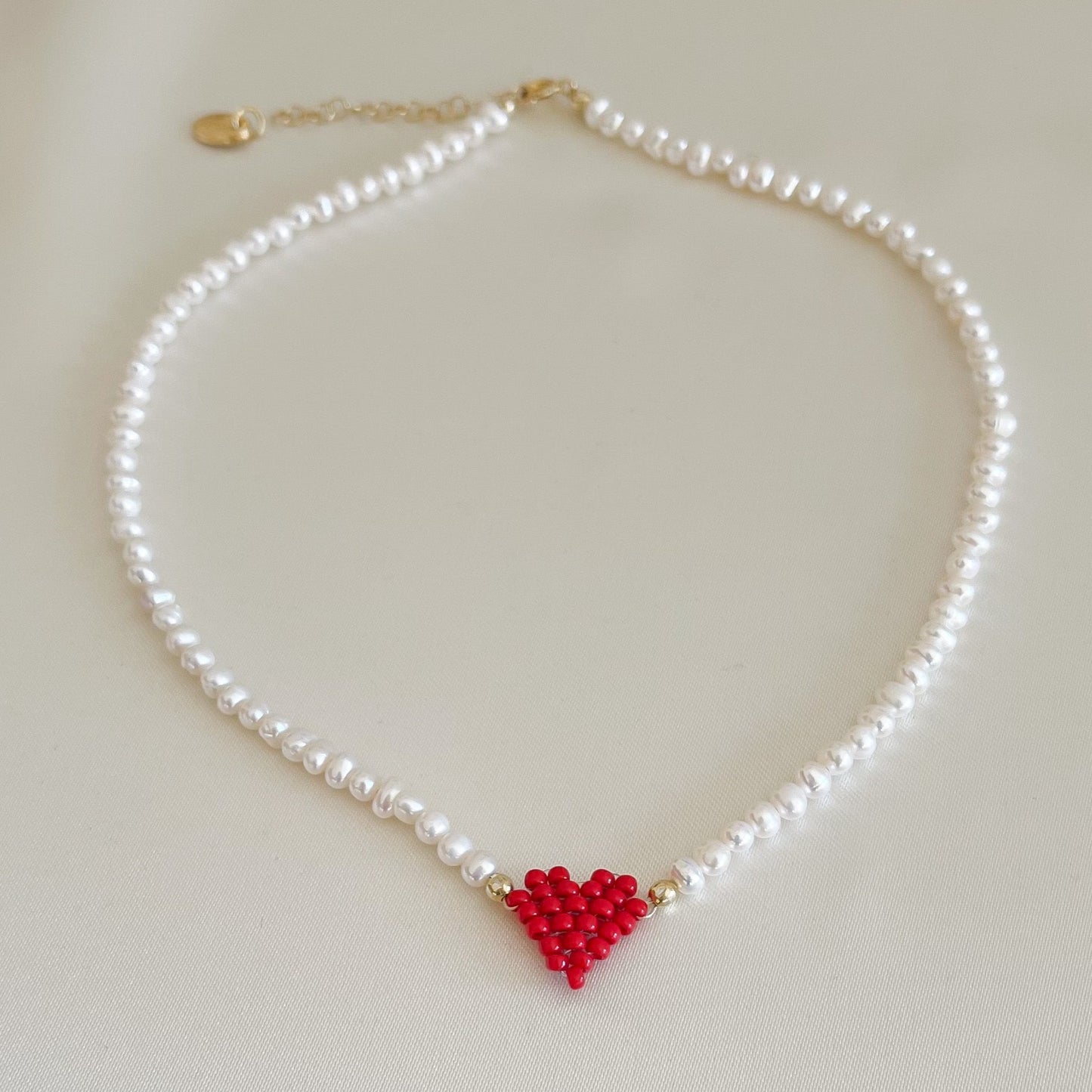 Collana di perle di fiume modello girocollo-coker  con in centro cuore in perline toho di colori diversi.  La collana CUORE nasce con lo scopo di celebrare l'amore.  MATERIALE: perle di fiume, perline toho, componenti e moschettone in argento 925 con galvanica color oro. DIMENSIONI: lunghezza collana: circa 39 cm + 4 cm catenella CUORE in perline di diversi colori a scelta: smeraldo-verde acqua-blu-vioa-pink- rosso scuro mat- rrosso-arancione mat-rosa baby-oro opaco mat