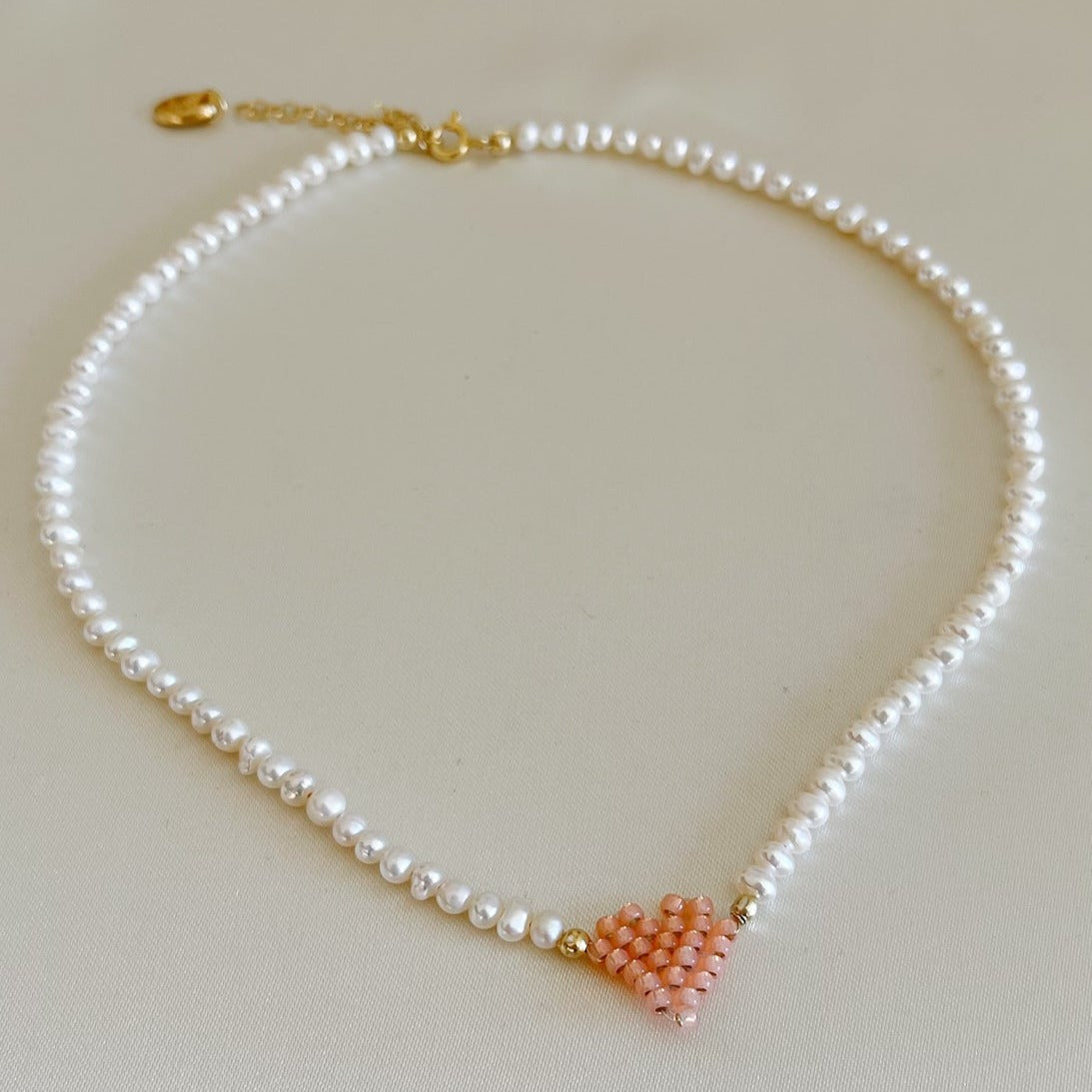 Collana di perle di fiume modello girocollo-coker  con in centro cuore in perline toho di colori diversi.  La collana CUORE nasce con lo scopo di celebrare l'amore.  MATERIALE: perle di fiume, perline toho, componenti e moschettone in argento 925 con galvanica color oro. DIMENSIONI: lunghezza collana: circa 39 cm + 4 cm catenella CUORE in perline di diversi colori a scelta: smeraldo-verde acqua-blu-vioa-pink- rosso scuro mat- rrosso-arancione mat-rosa baby-oro opaco mat