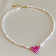 Carica l&#39;immagine nel visualizzatore di Gallery, Collana di perle di fiume modello girocollo-coker  con in centro cuore in perline toho di colori diversi.  La collana CUORE nasce con lo scopo di celebrare l&#39;amore.  MATERIALE: perle di fiume, perline toho, componenti e moschettone in argento 925 con galvanica color oro. DIMENSIONI: lunghezza collana: circa 39 cm + 4 cm catenella CUORE in perline di diversi colori a scelta: smeraldo-verde acqua-blu-vioa-pink- rosso scuro mat- rrosso-arancione mat-rosa baby-oro opaco mat